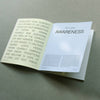 An open guided journal with text on both pages photographed against a grey-green surface.