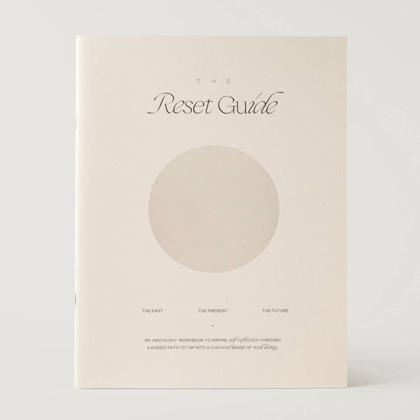 A cream-colored book titled 'The Reset Guide' with a minimalist design featuring a large beige circle on the front cover, photographed against a light gray background.