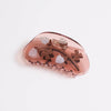 A translucent dusty rose hair claw clip decorated with small brown bows, white pineberry motifs, and subtle gold glitter accents, shown on a clean white background.