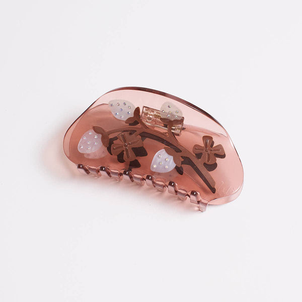 A translucent dusty rose hair claw clip decorated with small brown bows, white pineberry motifs, and subtle gold glitter accents, shown on a clean white background.