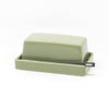 Green ceramic butter dish with lid and a small silver knife on a white background