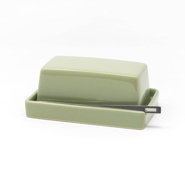 Green ceramic butter dish with lid and a small silver knife on a white background